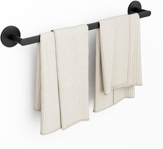 Matte black wall-mounted towel rack with two beige towels hanging on it against a white background.